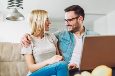 Neşeli çift rahatla ve dizüstü bilgisayar modern oturma odası, çalışma  