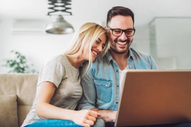 Neşeli çift rahatla ve dizüstü bilgisayar modern oturma odası, çalışma 