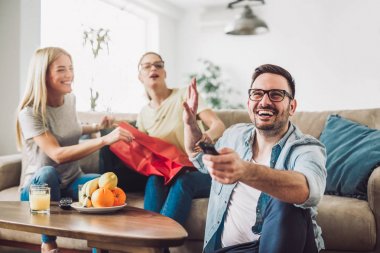 Sonra alışveriş torbalarıyla evde oturan genç kadınlar. Genç adam TV izlerken.