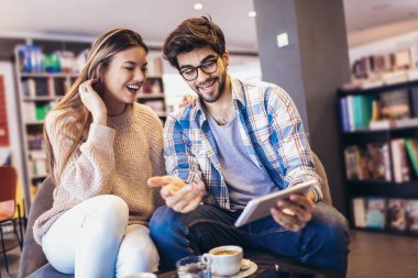 Genç çift dijital tablet kullanma ve having fun kapalı Cafe.