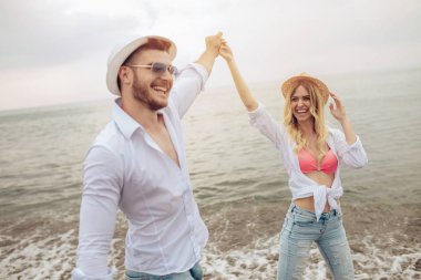 Kumsalda el ele tutuşan gülümseyen çift