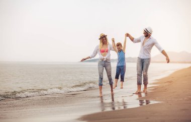 mutlu genç aile eğlenceli plaj var, koş ve atlama 