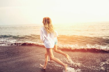 Romantik Çift sahilde eğleniyor. Mutlu çift sahilde günbatımında çalışan.