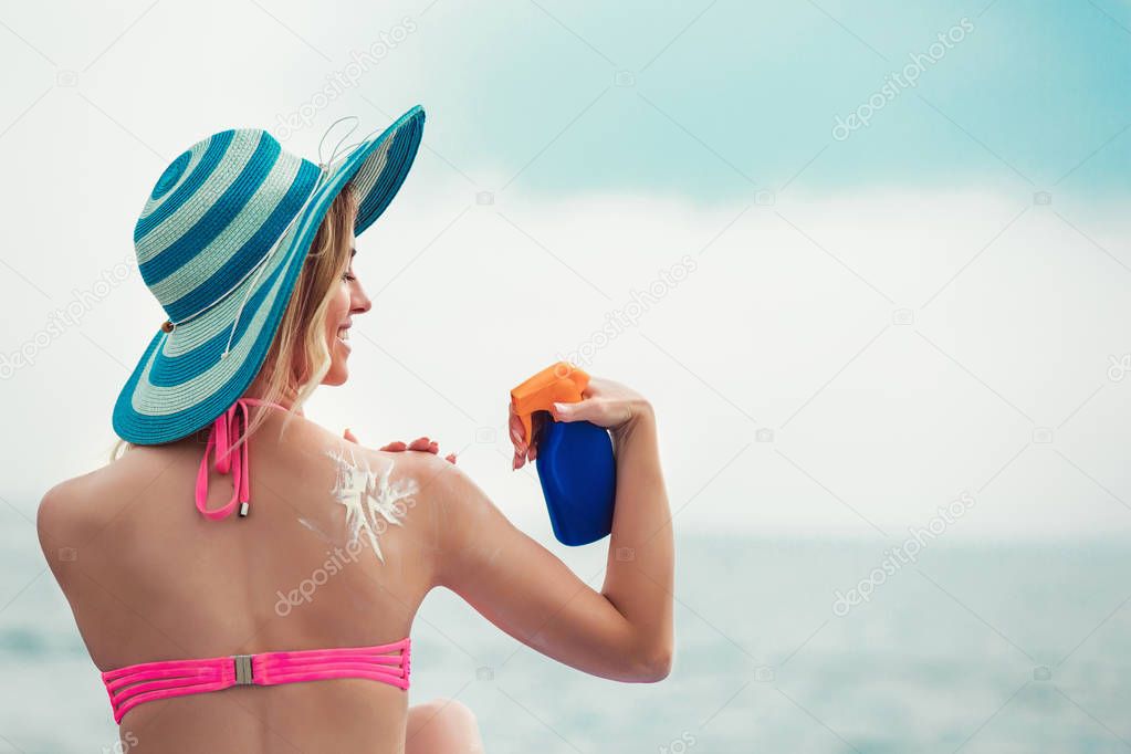 Young woman on beach applying sun block creme