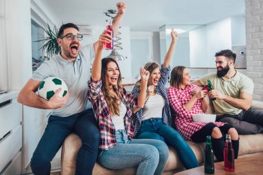 Mutlu arkadaşlar ya da futbol taraftarları televizyonda maç izleyip zaferi evde kutluyorlar. Dostluk, spor ve eğlence kavramı..