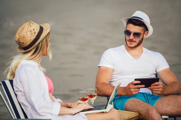 快乐的微笑情侣冲浪网和享受夏季在热带海滩使用笔记本电脑和数码片 — 图库照片