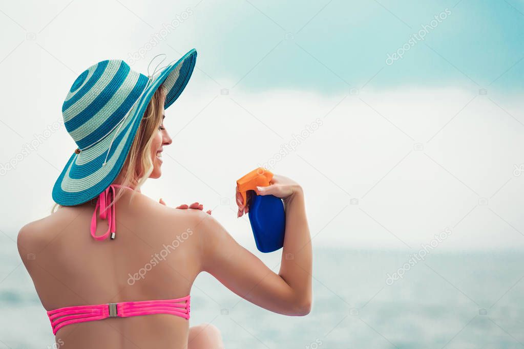 Young woman applying sun block creme on beach