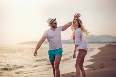 Eğleniyor kumsalda gün batımında romantik Çift.