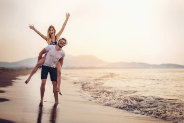 Neşeli genç kadın genç erkek piggybacking ve having fun.