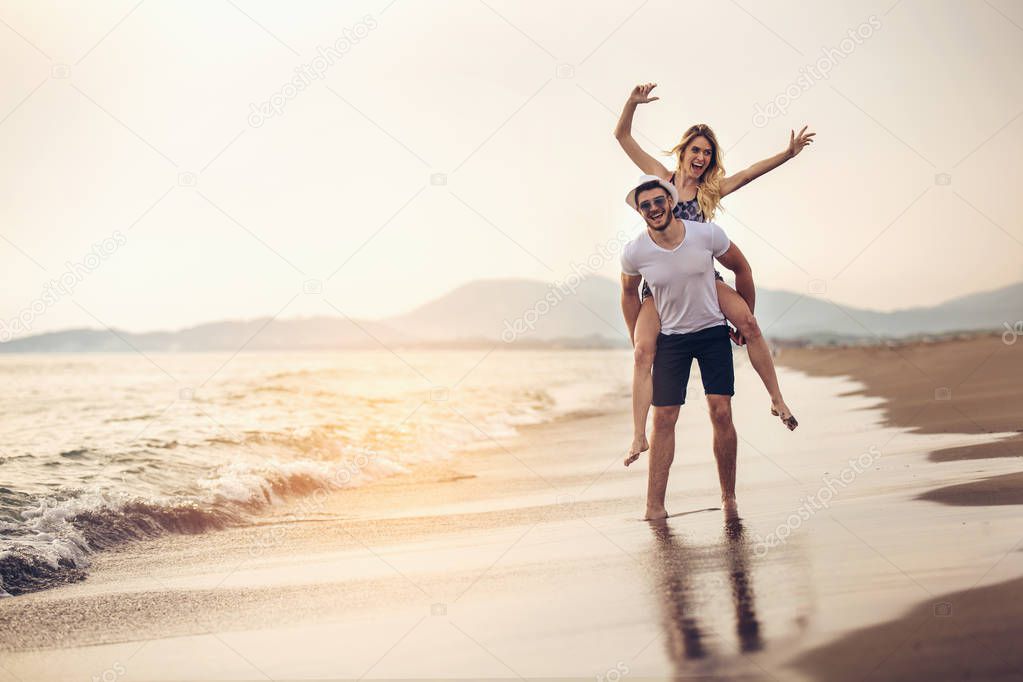 Joyful young woman piggybacking on young boyfriend and having fun.