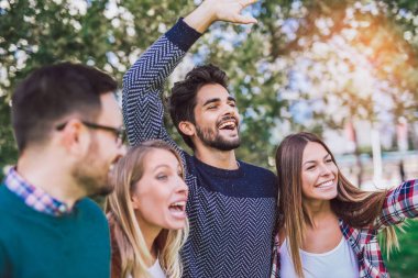 Bir grup genç parkta yürüyor. Arkadaşlar dışarıda eğleniyor.