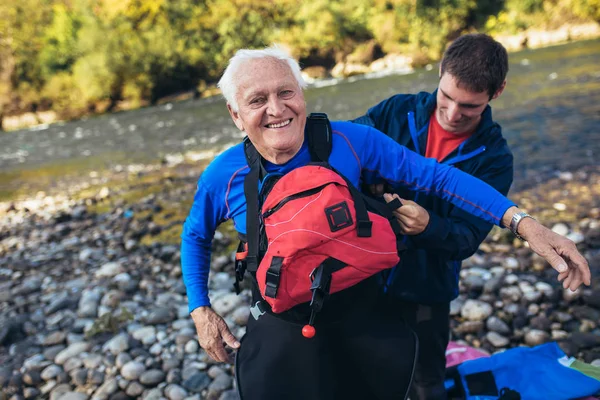 Homme âgé se préparant pour une excursion en kayak sur une rivière de montagne. — Photo