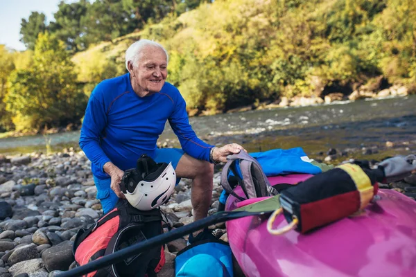 Uomo anziano che si prepara per il tour in kayak su un fiume di montagna. — Foto Stock