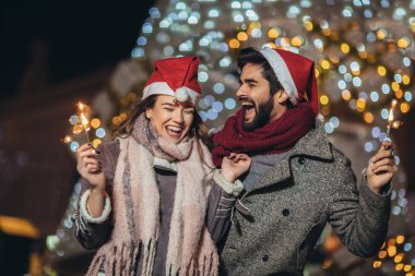 Genç çift, bayram ışıklarıyla havai fişek yakıyor.