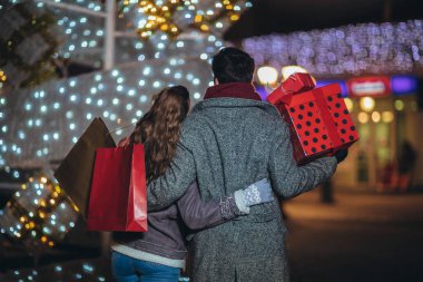 Walki sırasında Noel ışıkları arka plan üzerinde hediye çantası ile Çift