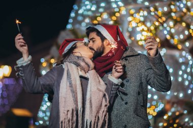 Genç çift, bayram ışıklarıyla havai fişek yakıyor.