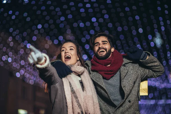 Pareja con bolsa de regalo en el fondo de luces de Navidad durante el walki —  Fotos de Stock