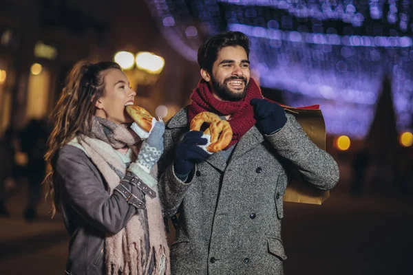 Jong stel gekleed in winterkleding met boodschappentassen ou — Stockfoto