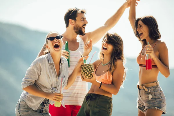 Gelukkige jonge mensen dansen op het strand en hebben plezier. — Stockfoto