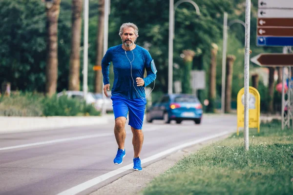 Aktywny starszy mężczyzna jogging w słoneczny dzień — Zdjęcie stockowe