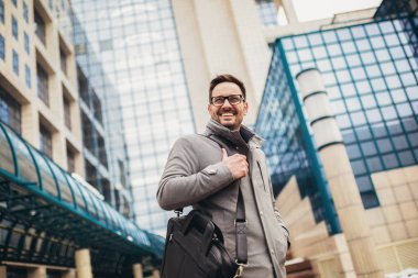 Genç işadamı büyük bir modern iş dünyasının önünde duruyor.