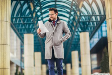 Elinde belgeler, kağıtlar tutan genç ve çekici bir iş adamı. Genç eş