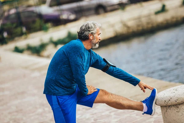 Senior fitness man training en het doen van training in de buurt van de zee. — Stockfoto