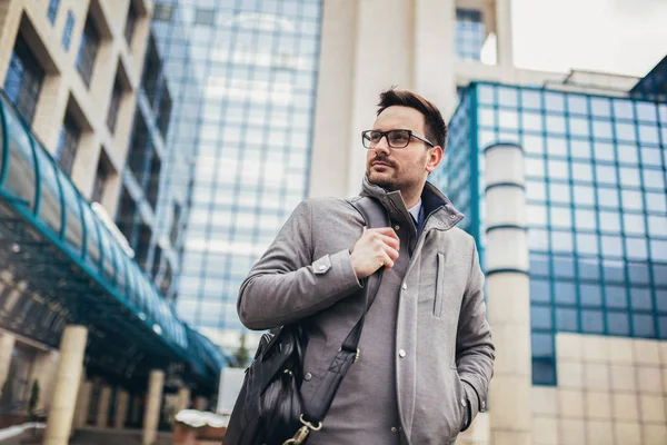 Young businessman standing in front of huge modern business buil — Stock Photo, Image