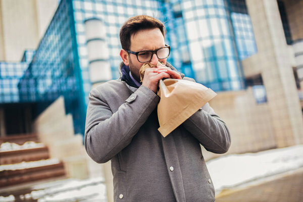 Businessman holding paper bag over mouth as if having a panic at