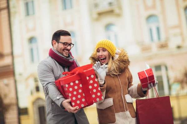 젊은 부부는 겨울 옷을 입고 선물 상자를 들고 밖으로 — 스톡 사진