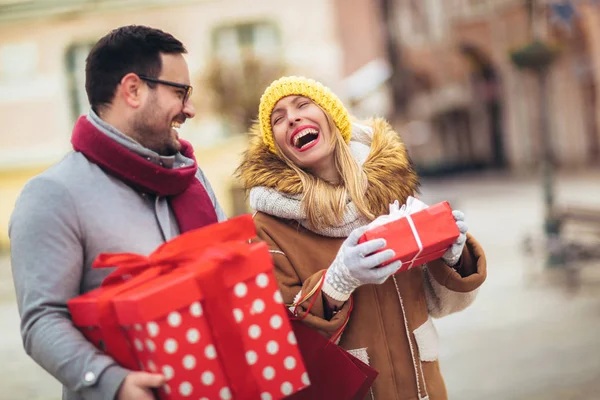 Jong stel gekleed in winter kleding houden geschenkdozen elkaar overtreffen — Stockfoto