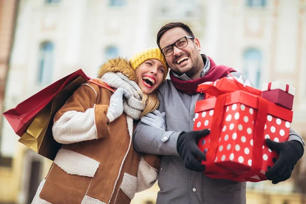 Young couple dressed in winter clothing holding gift boxes and s — ストック写真