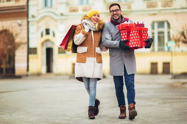 Young couple dressed in winter clothing holding gift boxes and s — ストック写真