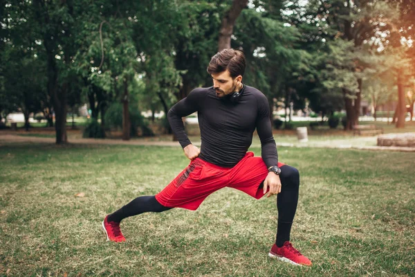 Sport człowiek rozciąga się w parku, robi ćwiczenia. — Zdjęcie stockowe