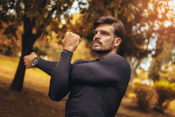 Esporte homem que se estende no parque, fazendo exercícios . — Fotografia de Stock