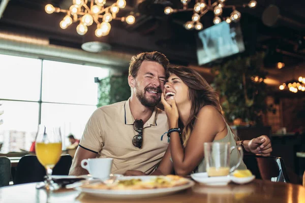 Young happy couple eating pizza in a restaurant — Stock Photo, Image