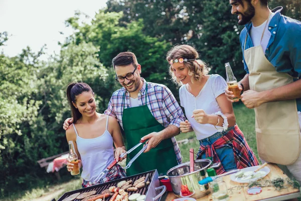 Jovens amigos se divertindo grelhando carne desfrutando de churrasqueira . — Fotografia de Stock