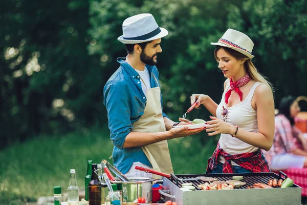 Young friends having fun grilling meat enjoying barbecue party. — Stock Photo, Image