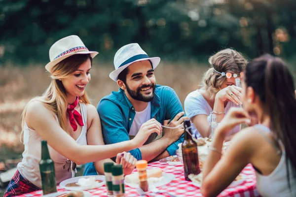 Groep vrienden genieten van een lunchtijd samen in de natuur. — Stockfoto