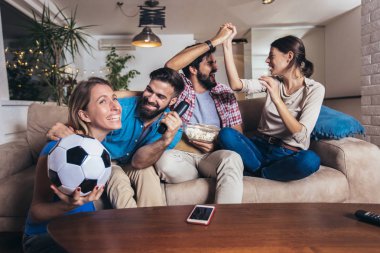 Arkadaşlar evde, evde futbol maçı izleyerek eğleniyorlar..