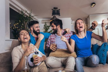 Arkadaşlar evde, evde futbol maçı izleyerek eğleniyorlar..