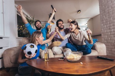 Arkadaşlar evde, evde futbol maçı izleyerek eğleniyorlar..