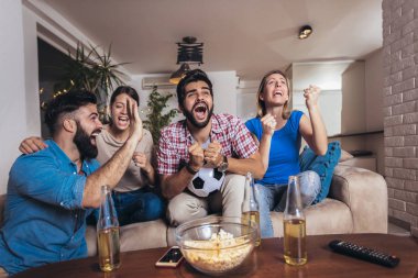 Arkadaşlar evde, evde futbol maçı izleyerek eğleniyorlar..
