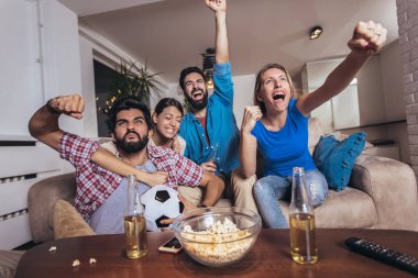 Arkadaşlar evde, evde futbol maçı izleyerek eğleniyorlar..