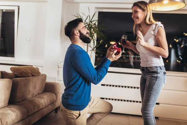 Förvånad ung kvinna ler medan hennes pojkvän föreslår henne. — Stockfoto