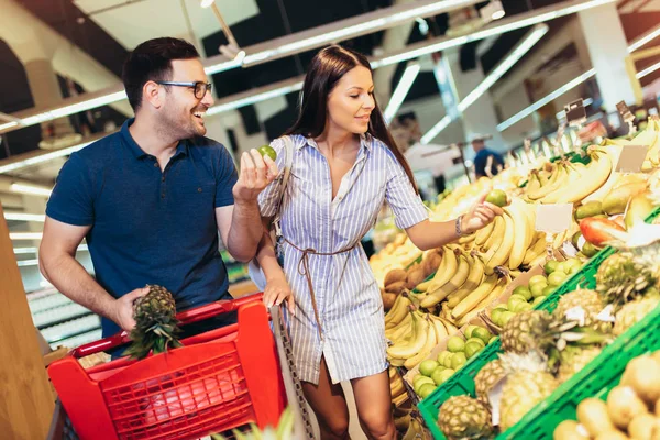Щаслива пара в супермаркеті купує свіжі фрукти разом — стокове фото