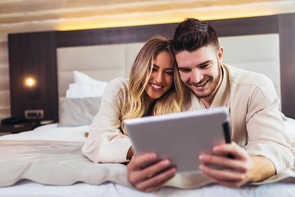 Happy couple using digital tablet while lying together in bed in — Stock Photo, Image