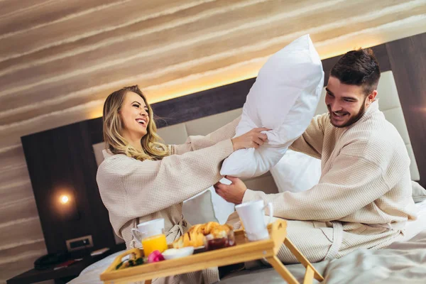 Felice coppia avendo lotta cuscino in camera d'albergo — Foto Stock