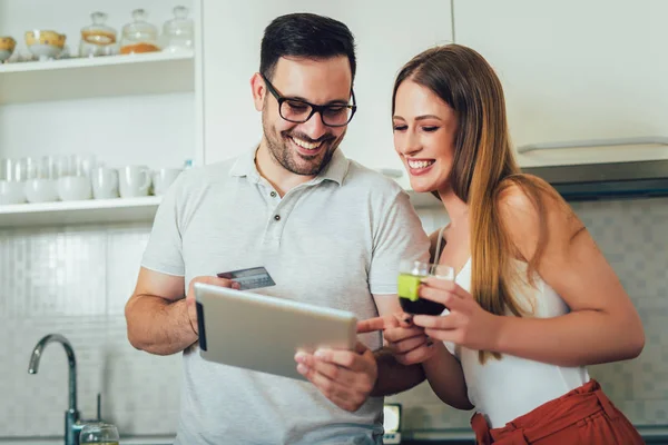 Lachende paar met behulp van digitale tablet en een creditcard bij u thuis — Stockfoto