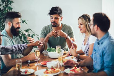 Neşeli gençler yemekte otururken yemeğin tadını çıkarıyorlar.